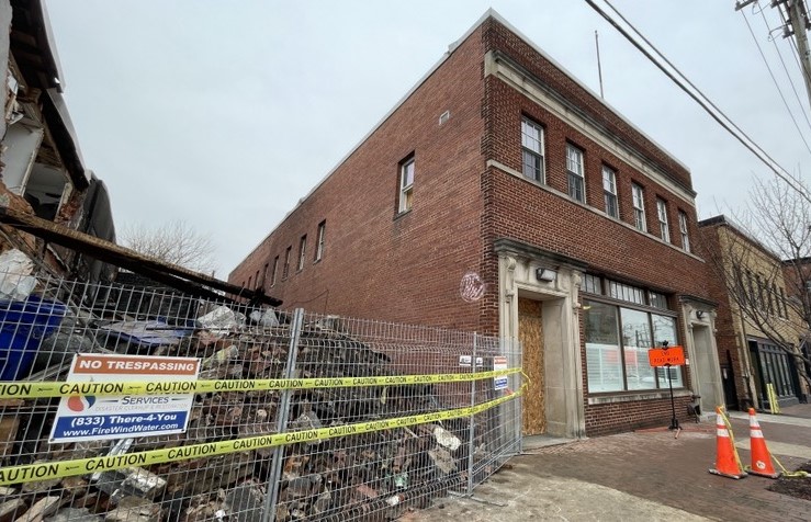 A brown building next to a pile of bricks and yellow caution tape.