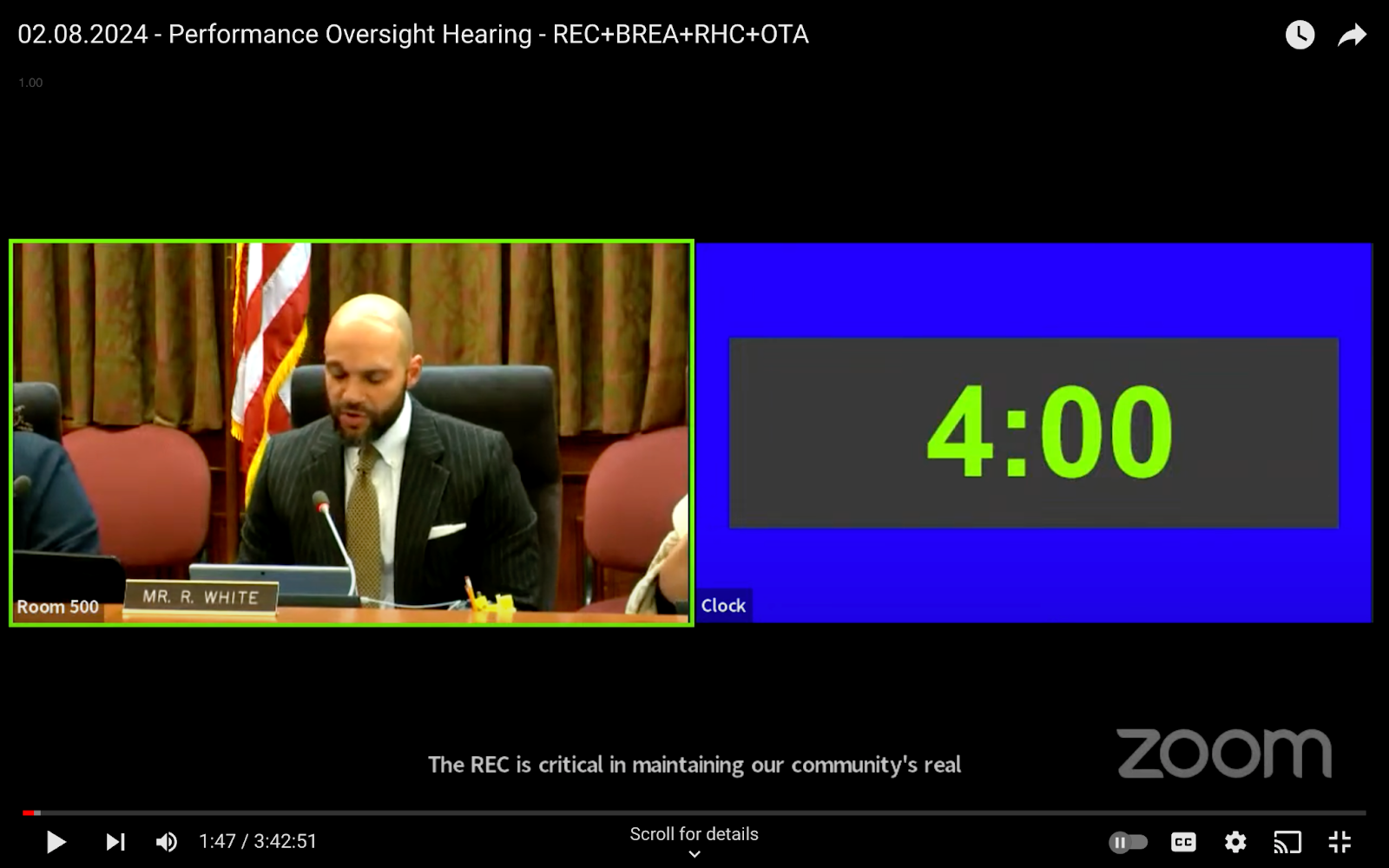A Black man sits on a dais in front on a YouTube stream.
