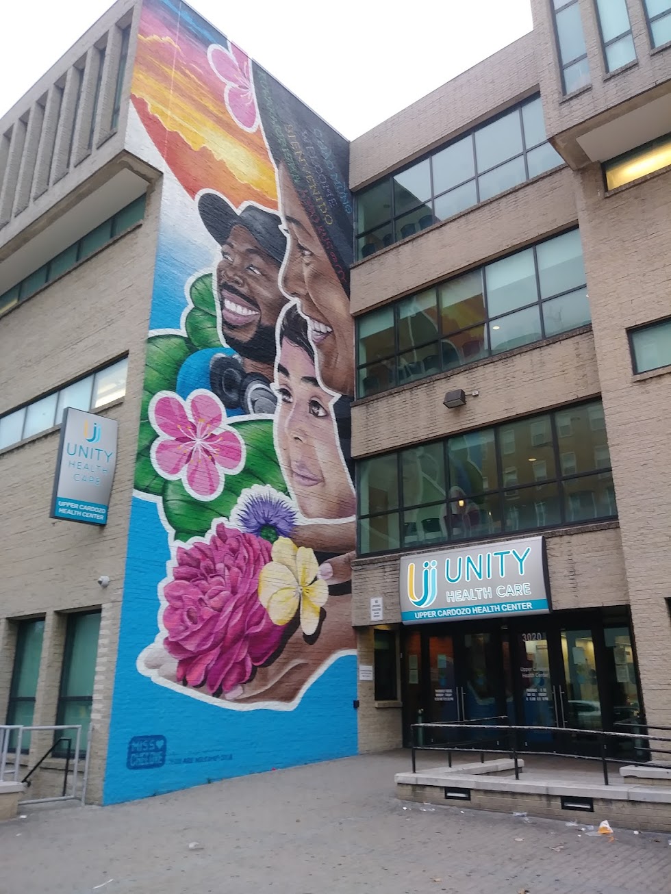 A blue mural with faces on a wall next to the entry to a Unity facility.