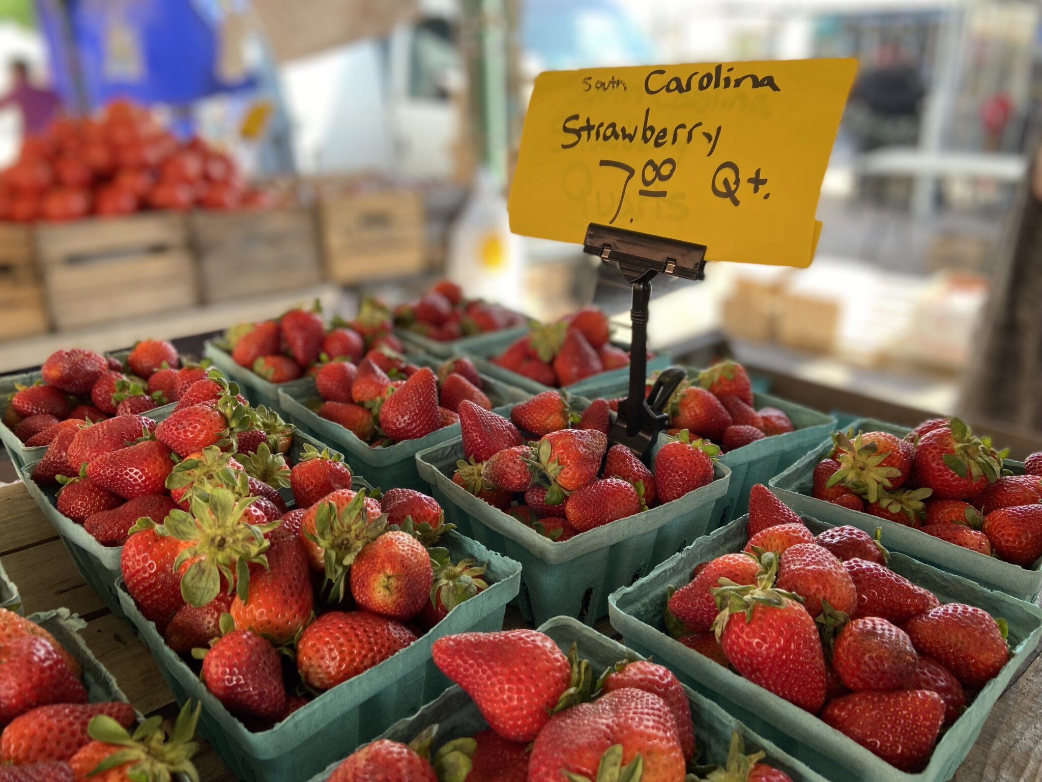 Several baskets of strawberries sit on a table. A yellow, $7.00, price tag is above them.
