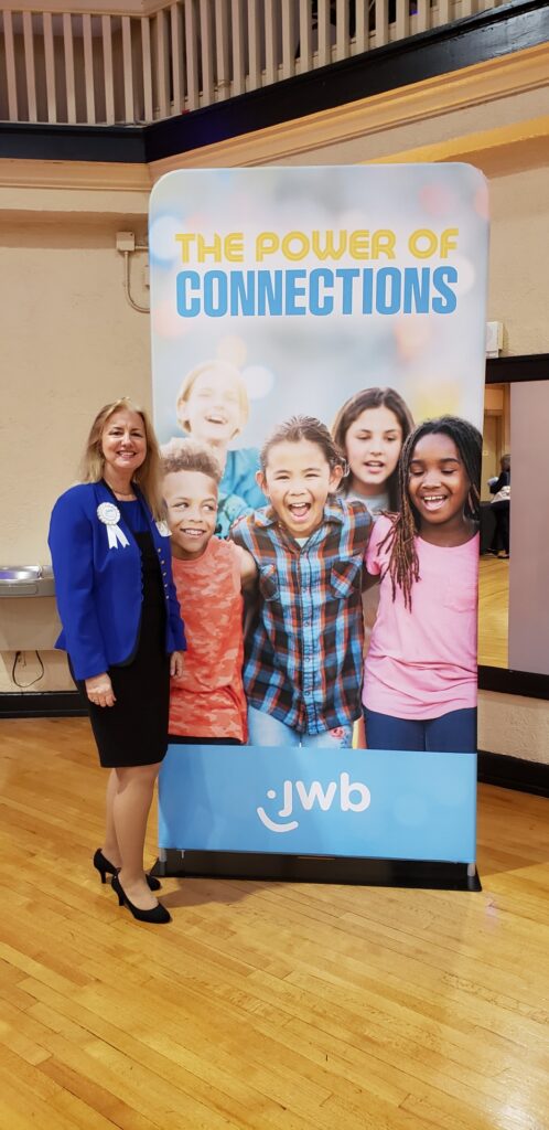 Woman stands in front of a poster with smiling children.