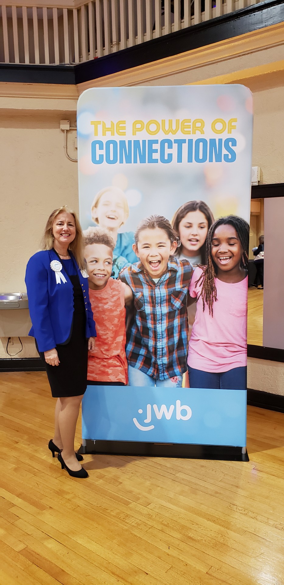 Woman stands in front of a poster with smiling children.