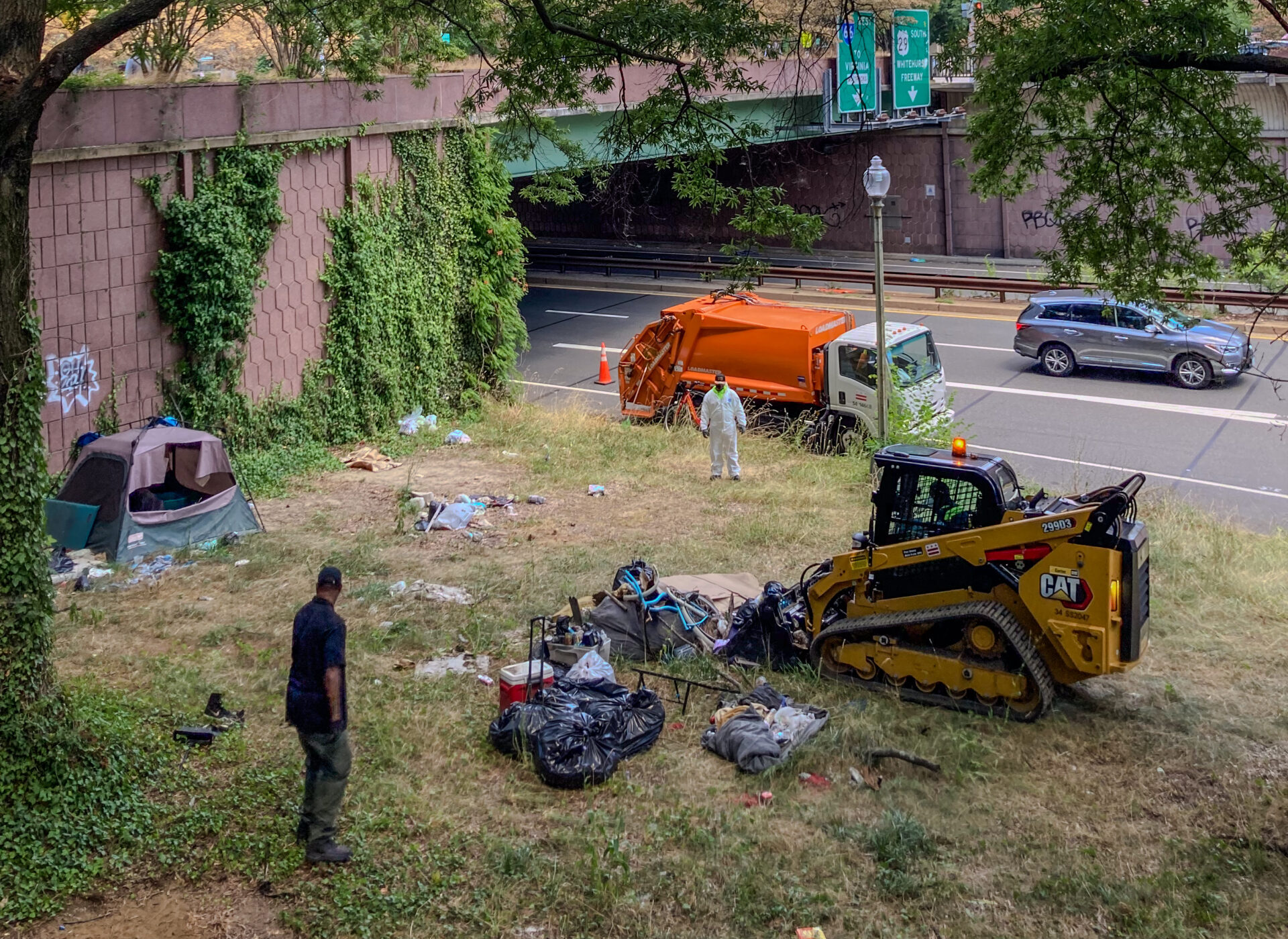 Yellow machine clearing trash on a grass area near a road