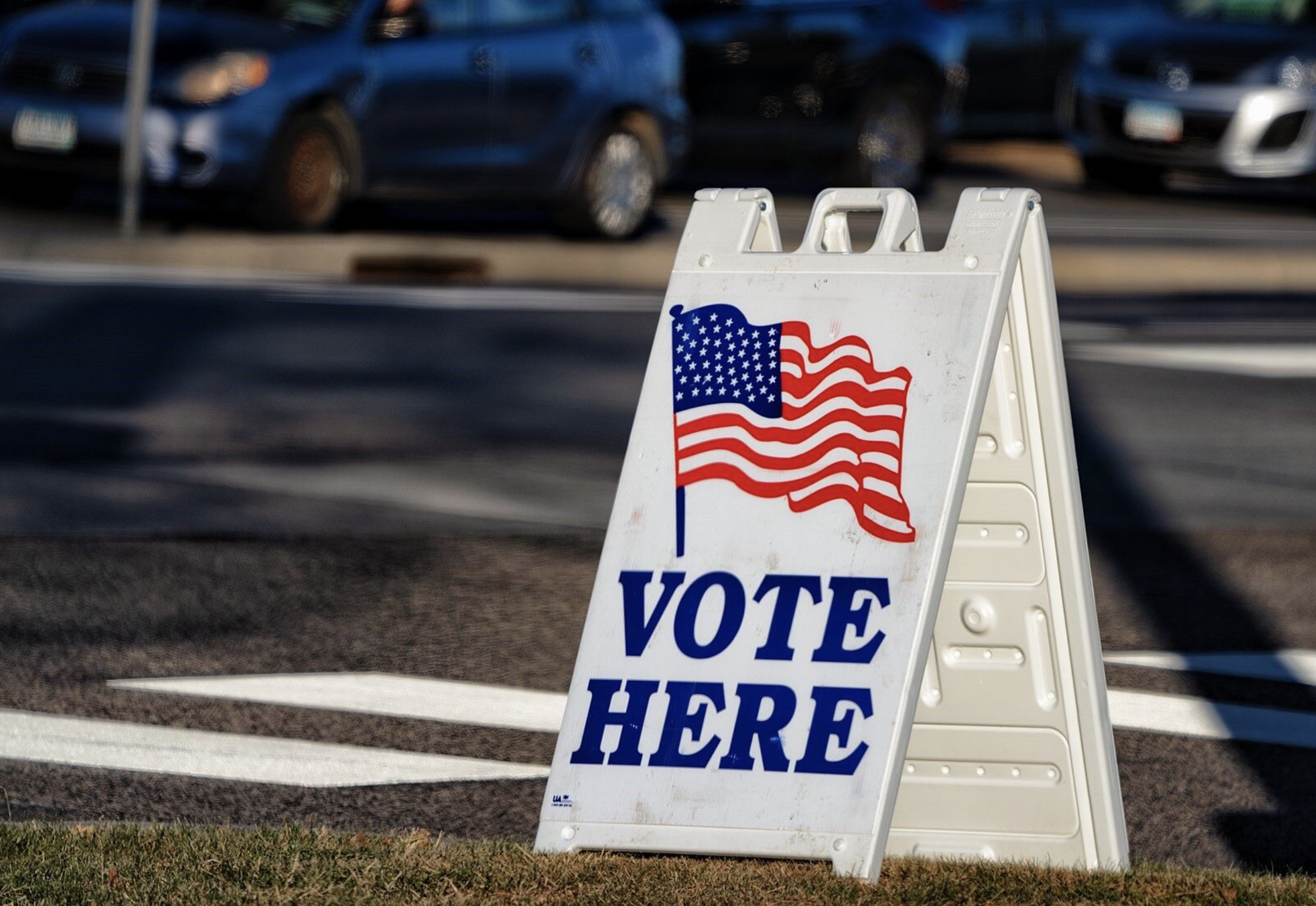 Photo of Vote Here sign with an American Flag illustration.