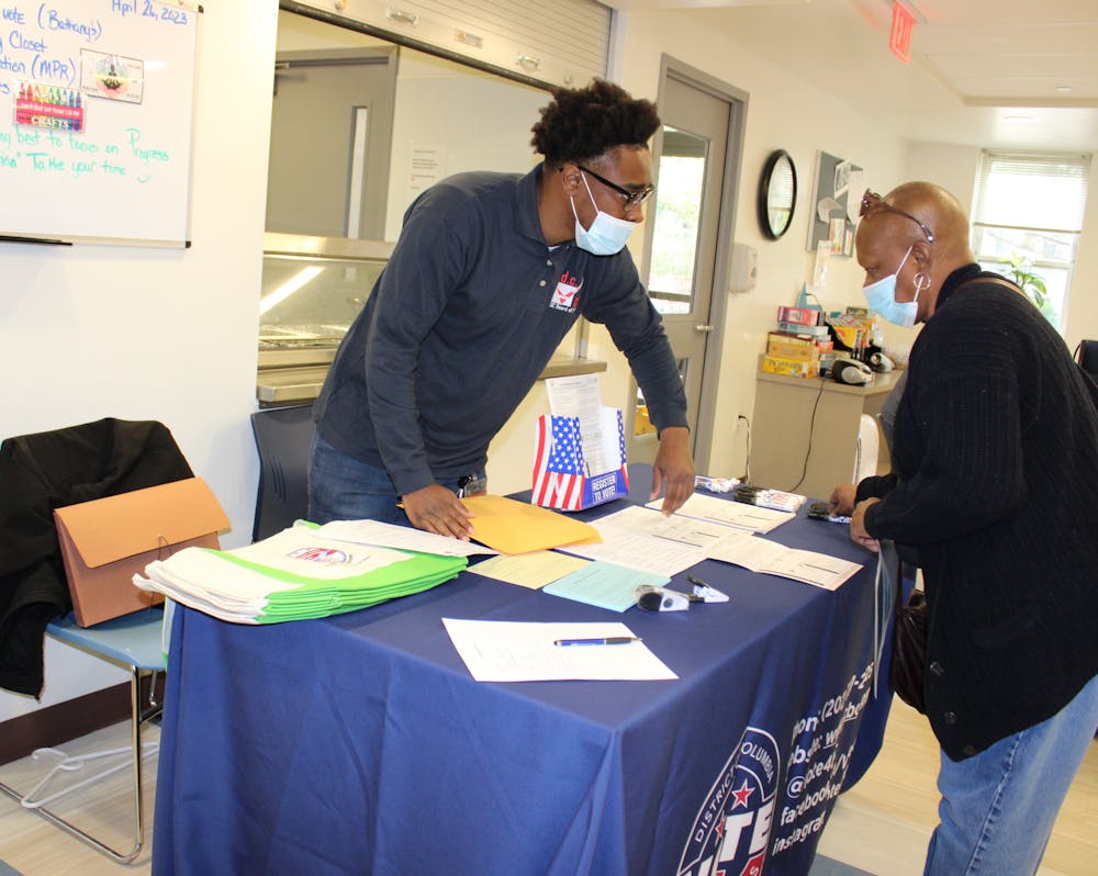 Two people talk over a table filled with ballots.
