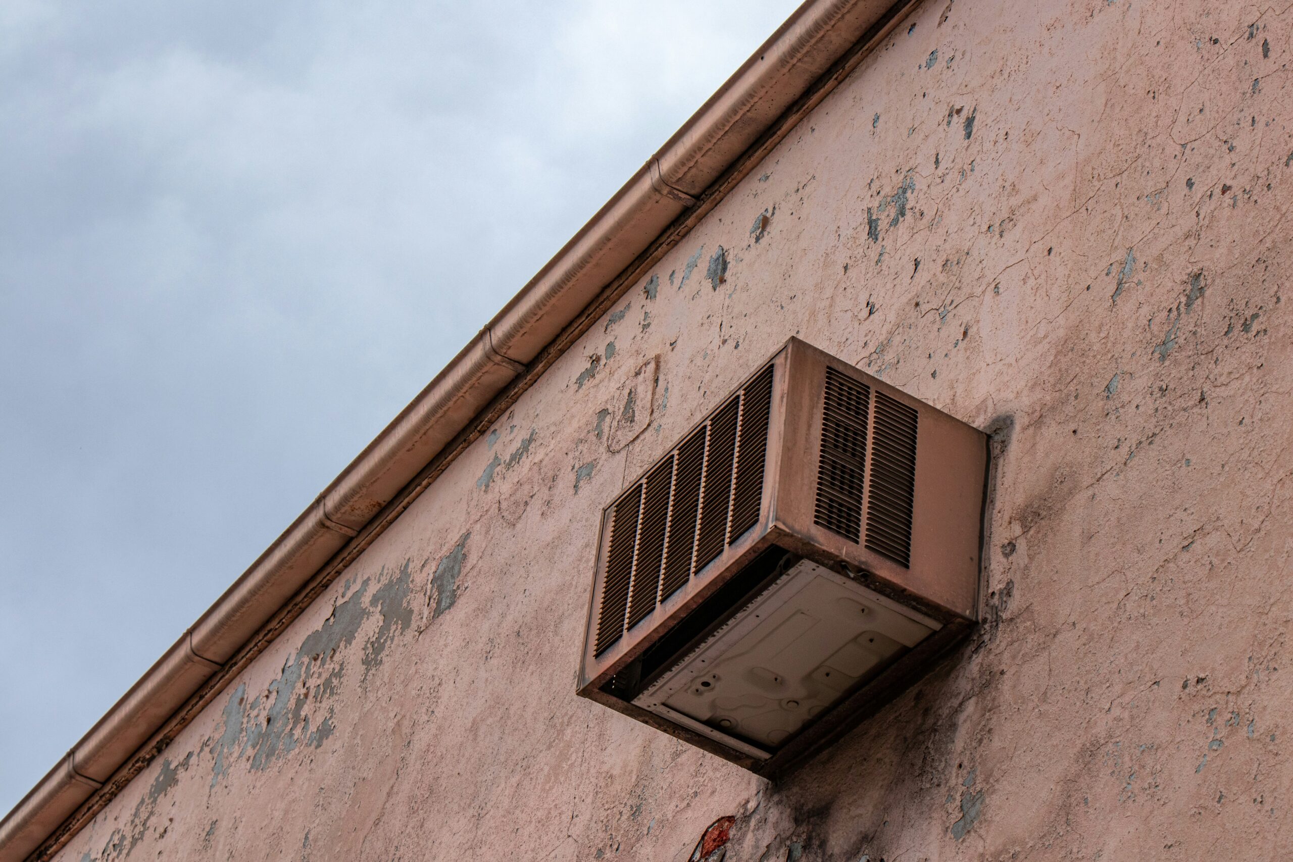 An air conditioner on the outside of a brown building.