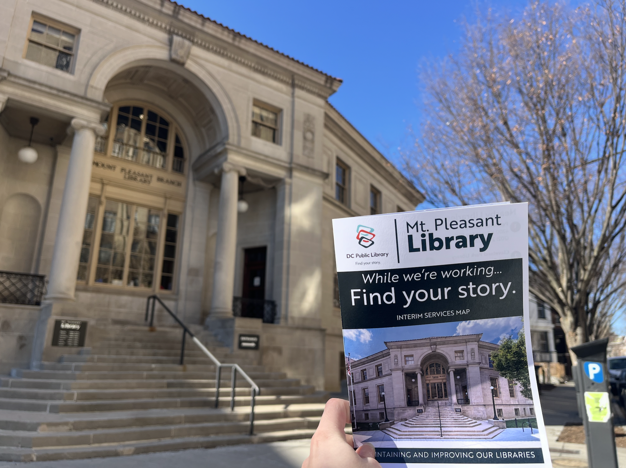 A pamphlet is held in front of an old building.