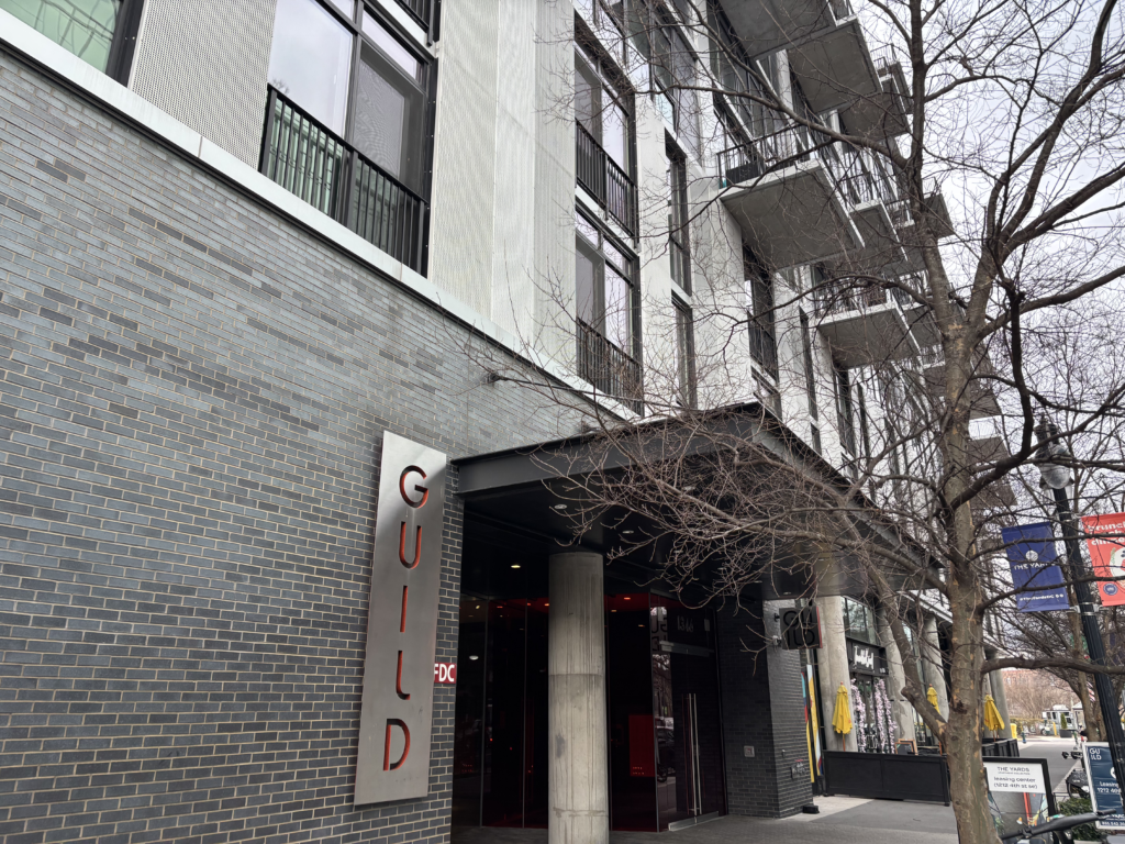 A grey apartment building with a sign reading "GUILD" in red letters.