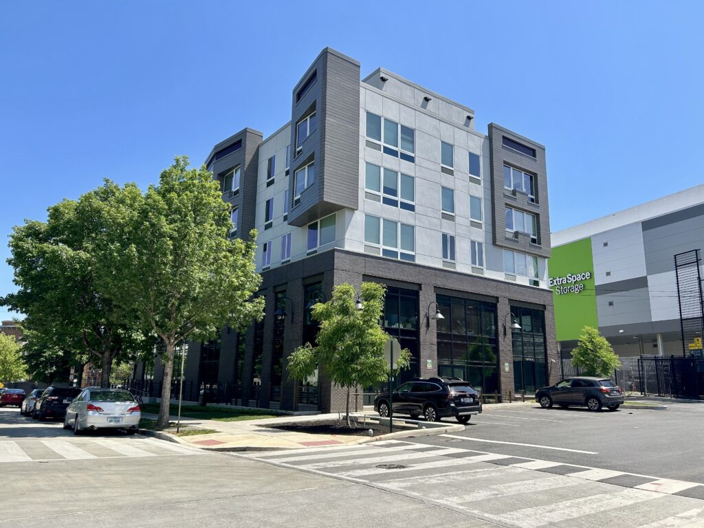 An unmarked grey building across the street is a domestic violence shelter.