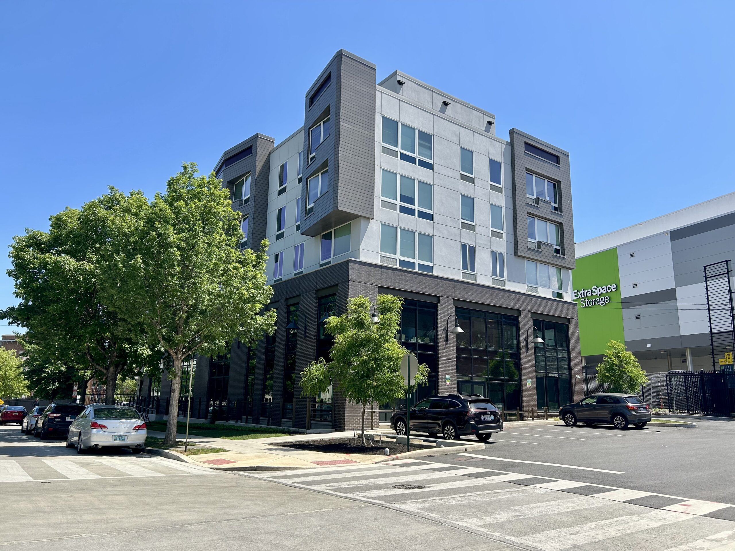 An unmarked grey building across the street is a domestic violence shelter.